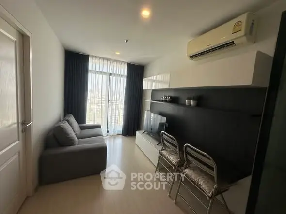 Modern living room with sleek furniture and large window offering natural light.