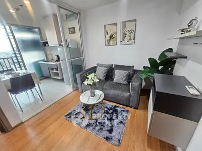Modern living room with cozy sofa and stylish decor adjacent to a compact kitchen area.