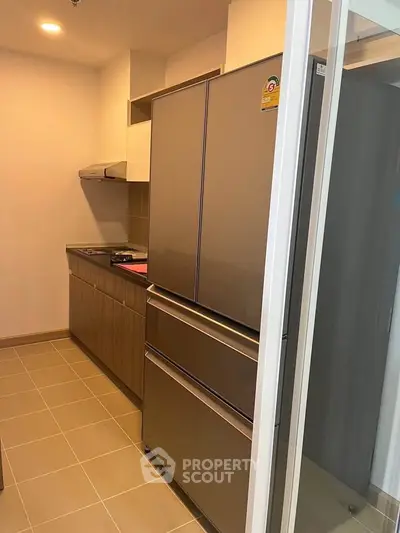 Modern kitchen with sleek appliances and closed layout, featuring a large fridge and ample storage space.