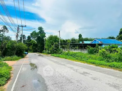 Scenic rural road with lush greenery and a quaint house, perfect for tranquil living.