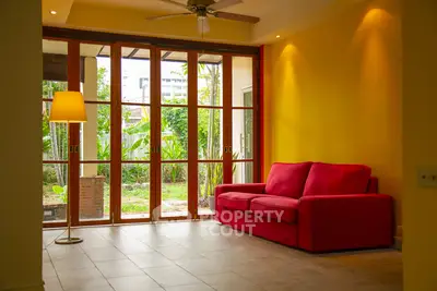 Bright living room with red sofa and garden view through large windows.