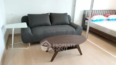 Cozy living room with modern sofa and coffee table, adjacent to a bedroom with a stylish bed.