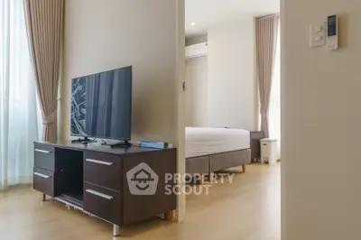 Modern apartment interior with TV and bedroom view, featuring stylish decor and natural light.