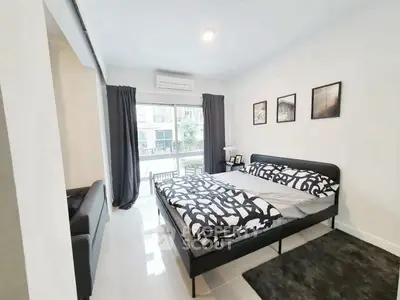 Modern bedroom with stylish decor and large window offering natural light in a contemporary apartment.