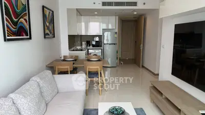 Modern living room with open kitchen, stylish decor, and cozy seating area.