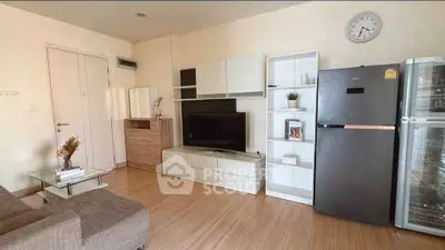 Modern living room with sleek furniture and large TV, featuring a stylish fridge and wooden flooring.
