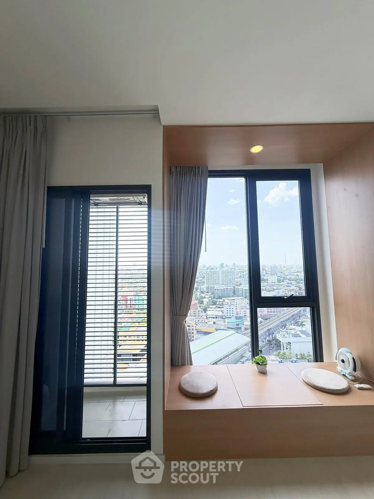 Modern apartment with stunning city view from large windows and cozy seating area.