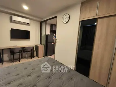 Modern bedroom with stylish decor, featuring a wall-mounted TV, air conditioning, and sleek furniture.