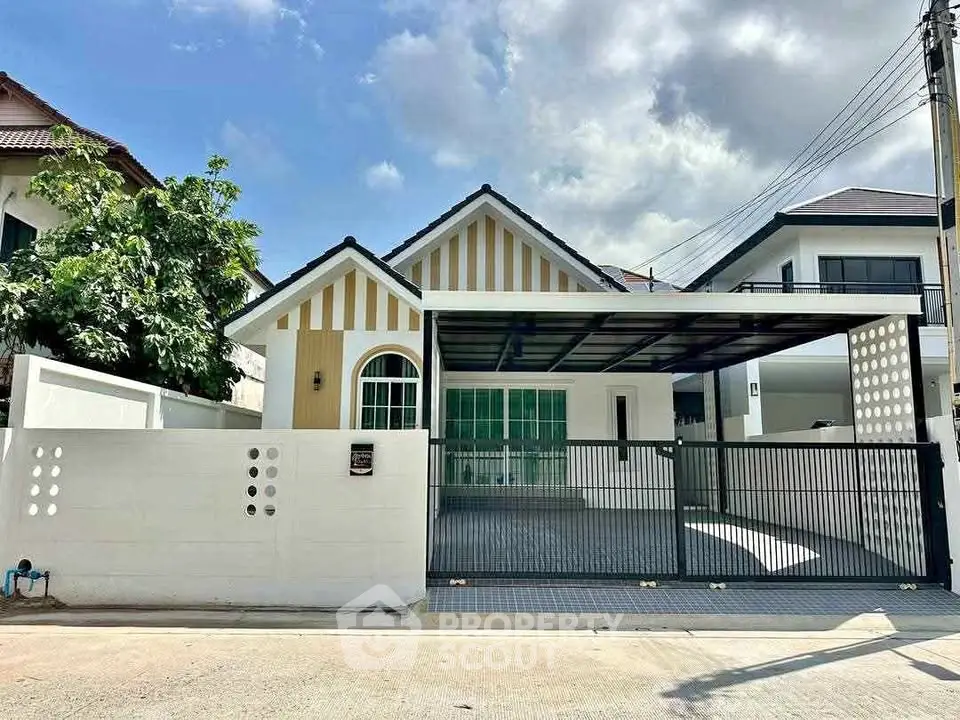 Charming single-story house with gated driveway and modern facade under a clear sky.
