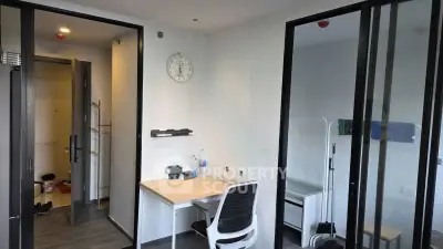Modern study room with sleek desk and chair, glass partitions, and minimalist decor.