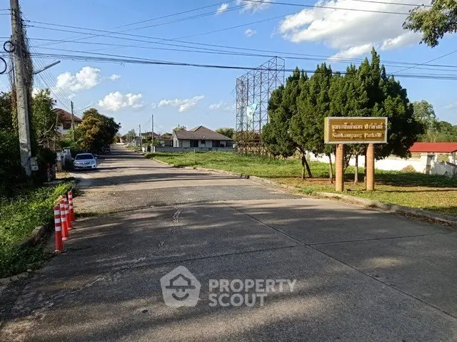 Charming suburban street view with lush greenery and clear blue sky.
