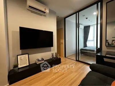 Modern living room with sleek design and wooden flooring, featuring a wall-mounted TV and air conditioning.