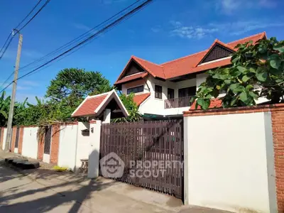 Charming two-story house with red-tiled roof and lush greenery, perfect for family living.
