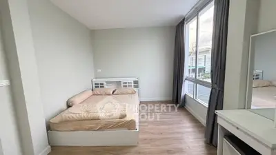 Modern bedroom with large window and minimalist design, featuring a cozy bed and wooden flooring.