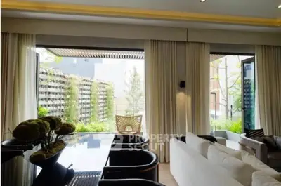 Luxurious living room with large windows and garden view, featuring elegant furniture and modern design.