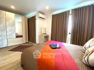 Spacious bedroom with modern decor and large windows in a stylish apartment.