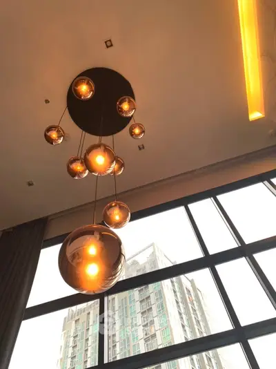 Modern apartment interior with stylish pendant lights and large windows showcasing city view.