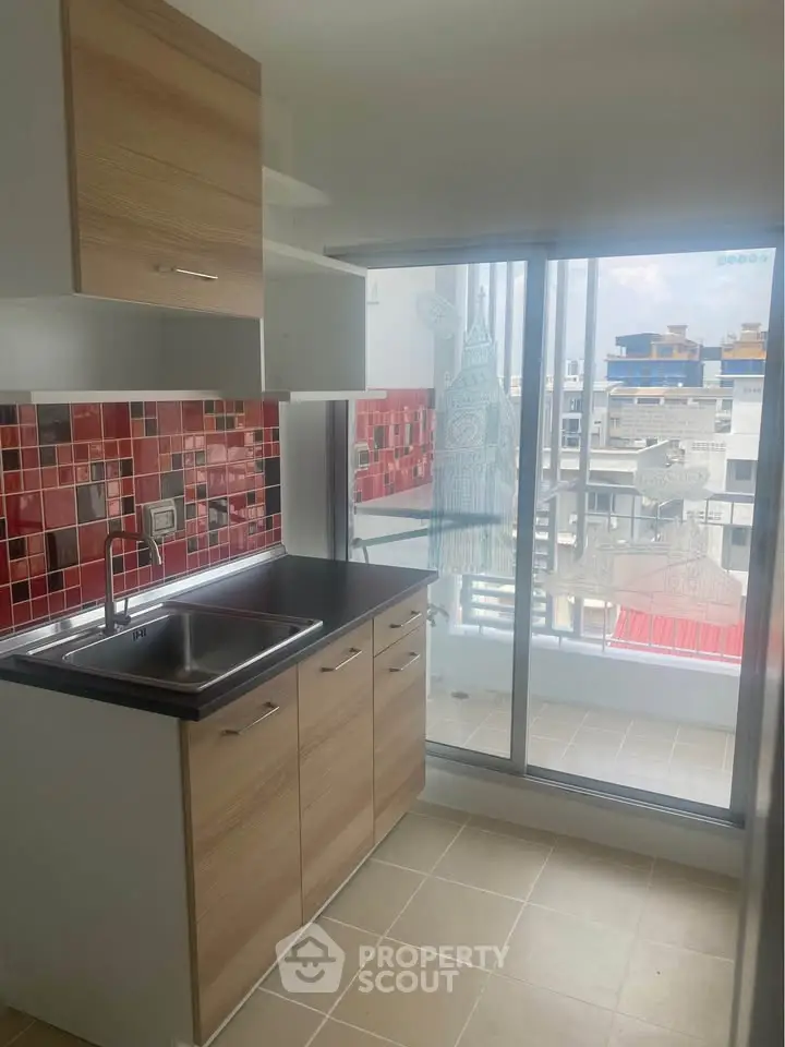 Modern kitchen with vibrant red backsplash and balcony view