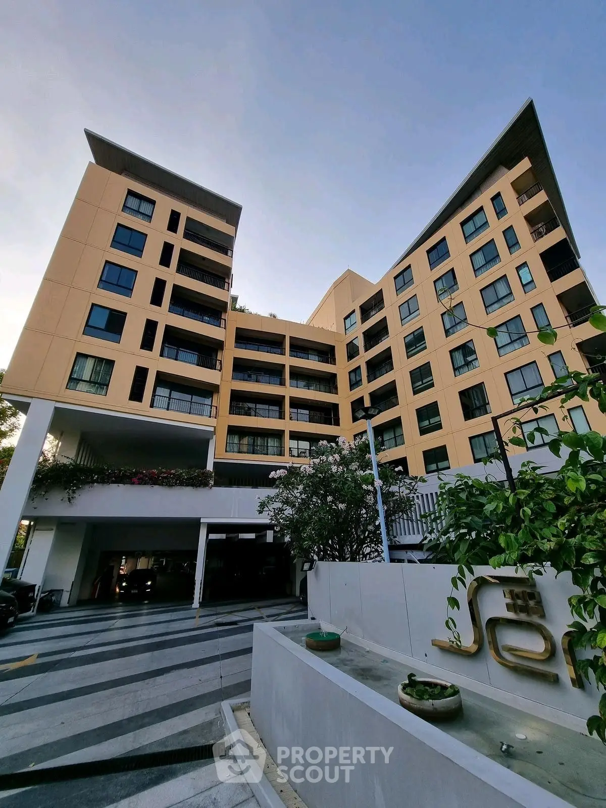 Modern multi-story apartment building with unique architectural design and lush landscaping.