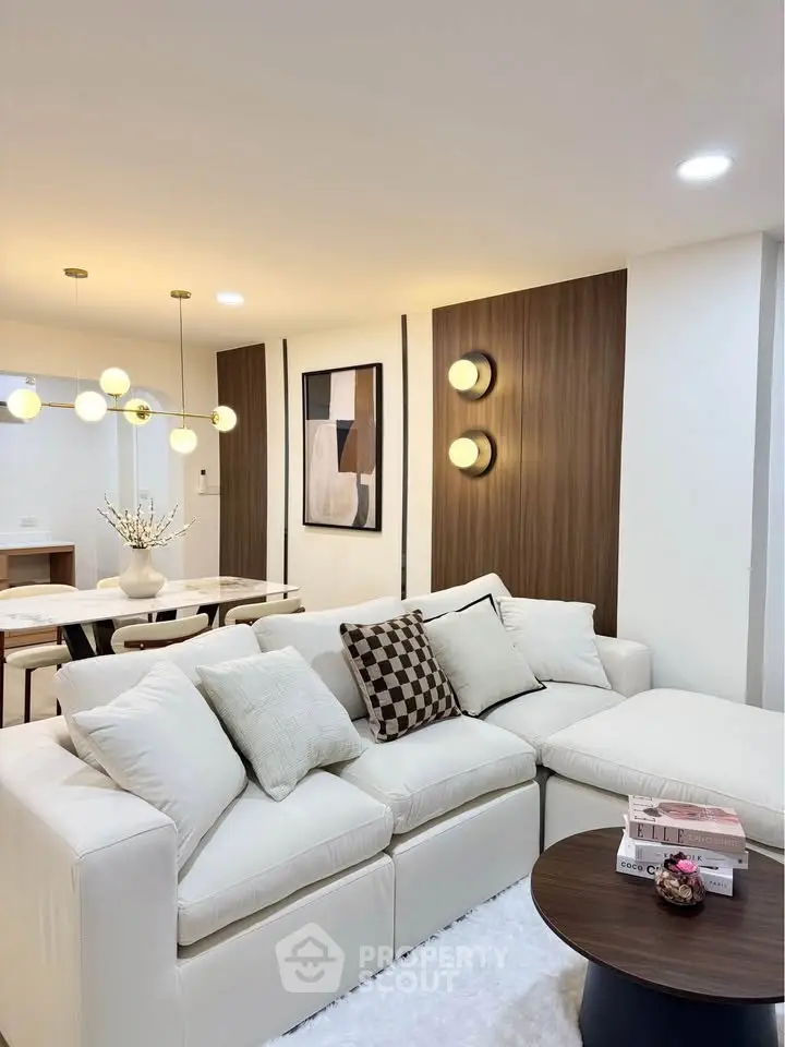 Elegant living room with modern decor, plush white sofa, and stylish lighting in a contemporary apartment.