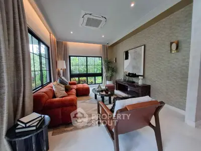 Luxurious living room with plush red sofas and large windows offering garden views.