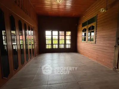 Spacious wooden interior with large windows and tiled floor, perfect for cozy living.