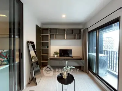 Modern living room with sleek furniture and large windows opening to a balcony with city views.