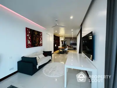 Modern living room with sleek decor and open layout, featuring a large TV and stylish furniture.