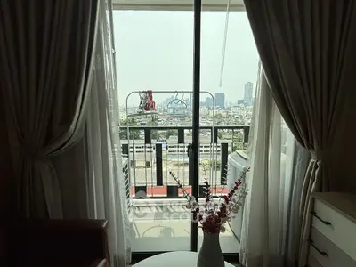 Charming apartment balcony with city view through elegant curtains, perfect for urban living.