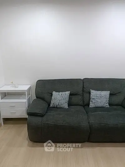 Cozy living room with plush dark sofa and stylish side table, perfect for relaxation.