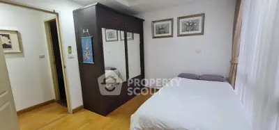 Cozy bedroom with wooden flooring and mirrored wardrobe, perfect for restful nights.