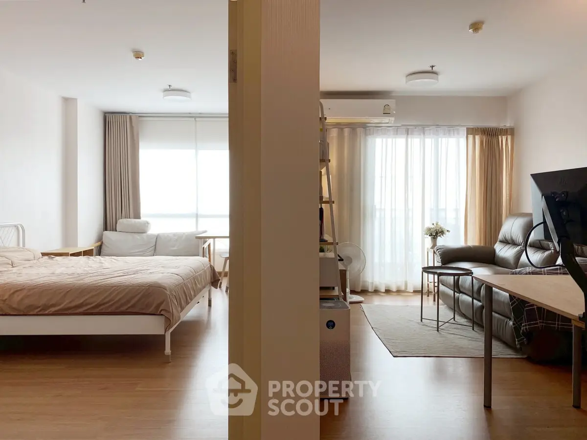 Spacious modern apartment with bedroom and living room, featuring large windows and cozy furnishings.