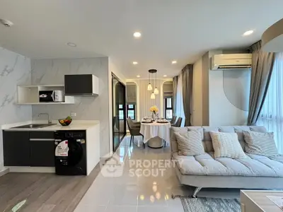 Modern open-plan living room with sleek kitchen and dining area, featuring stylish decor and natural light.