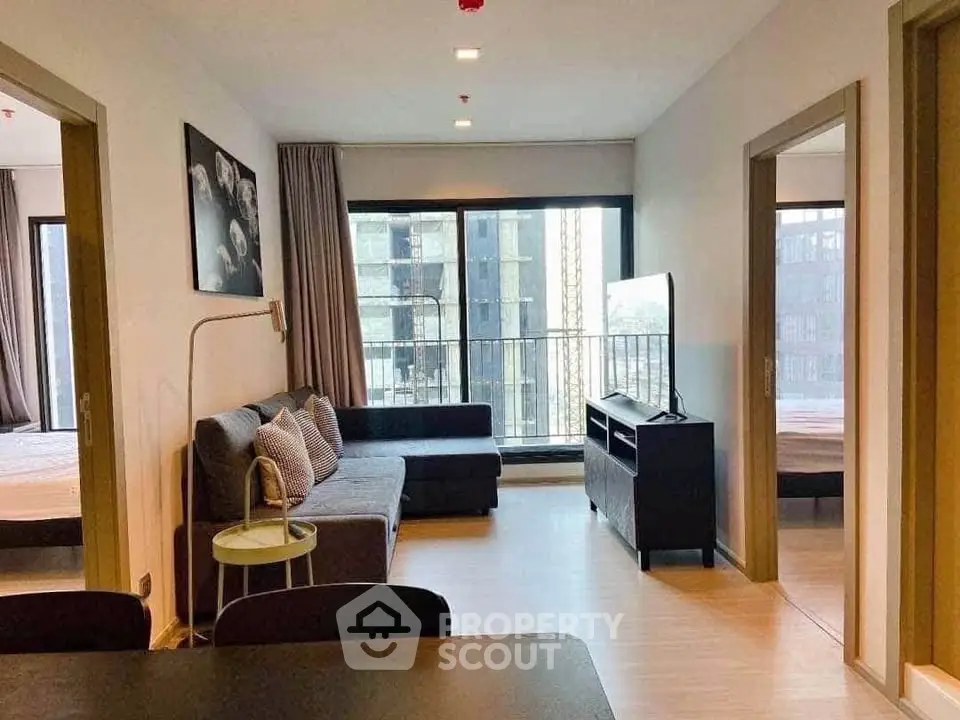 Modern living room with balcony access in a stylish apartment, featuring cozy seating and natural light.