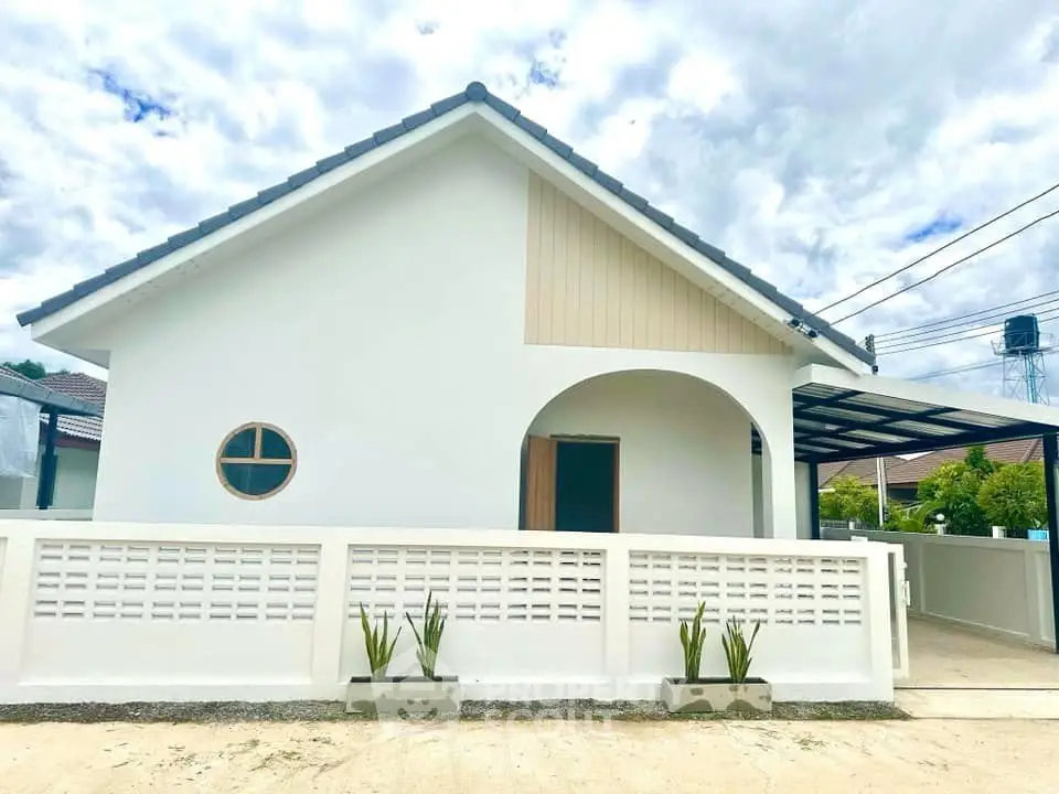 Charming single-story white house with modern design and spacious front yard, perfect for family living.