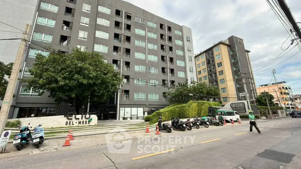 Modern urban apartment building with street view and motorbikes parked outside.