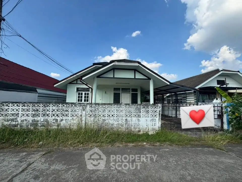 Charming single-story house with a white fence and spacious driveway under a clear blue sky.