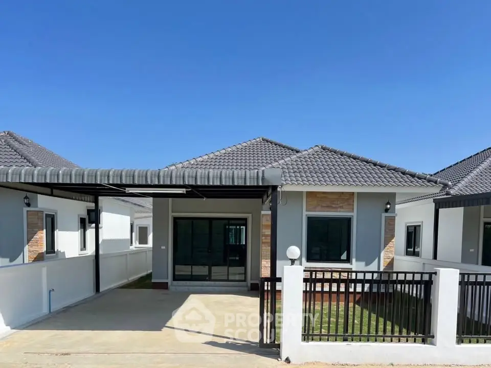 Charming single-story house with modern design and spacious driveway under clear blue sky.