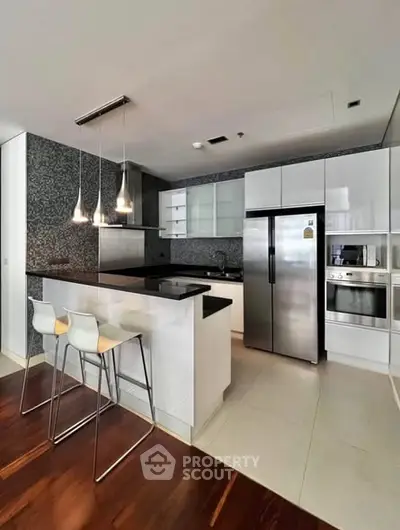 Modern kitchen with sleek design, featuring stainless steel appliances and stylish pendant lighting.