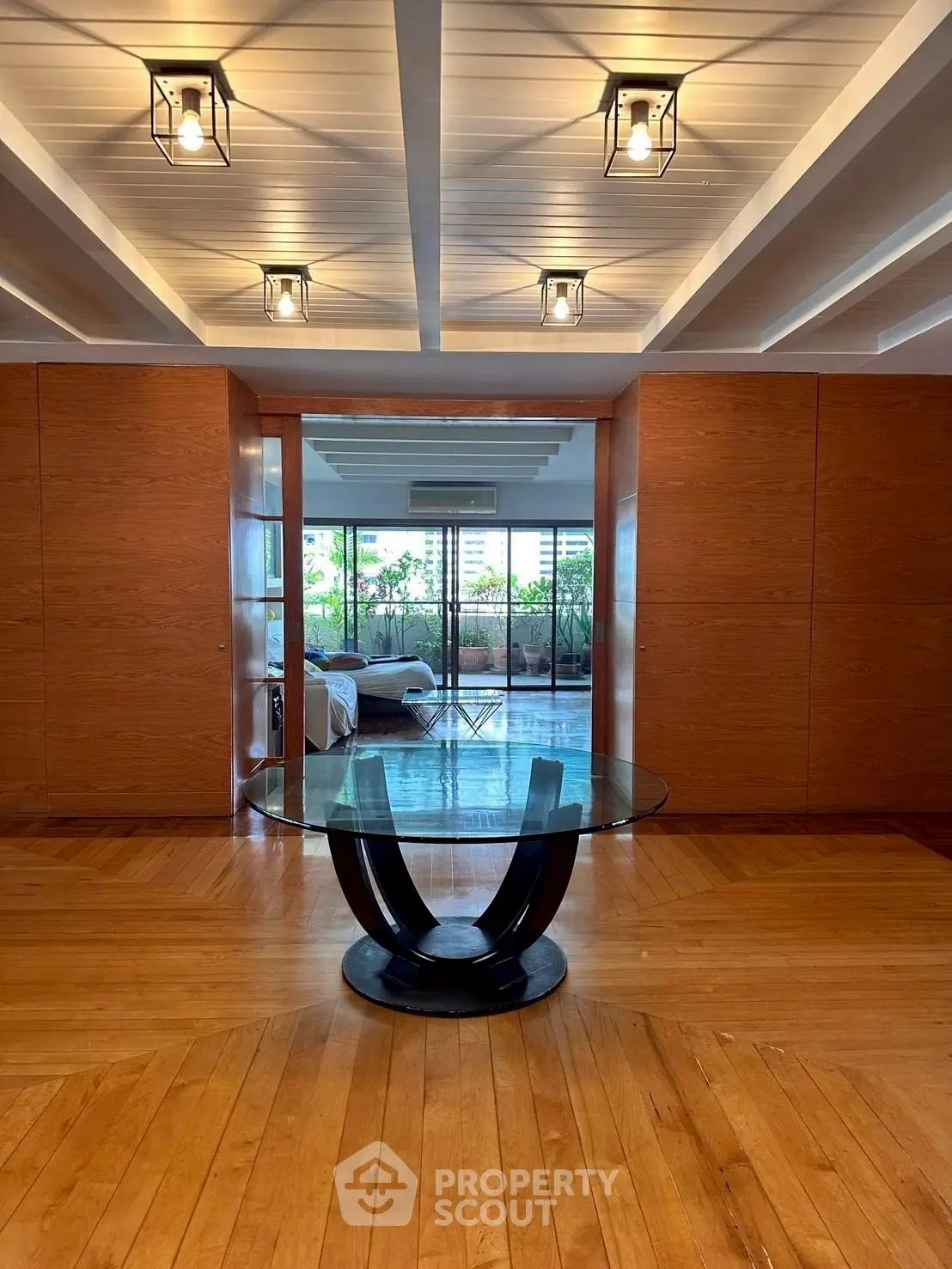 Luxurious interior with elegant glass table and wooden flooring leading to a spacious balcony.