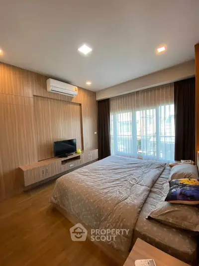 Modern bedroom with stylish decor and natural light through large windows.