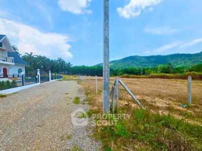 Scenic land plot with mountain views and adjacent house, ideal for development.
