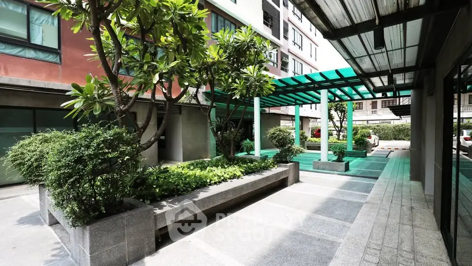 Modern apartment building entrance with lush greenery and sleek design