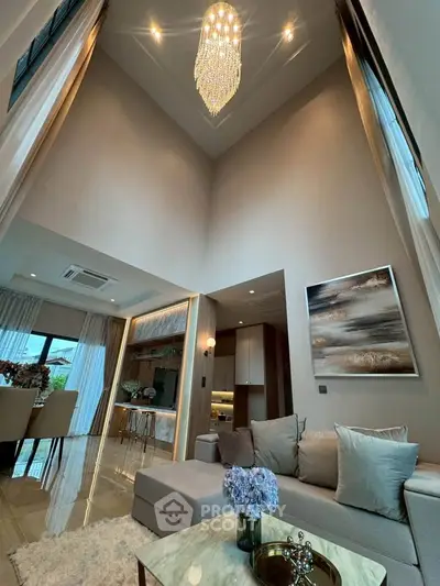 Luxurious high-ceiling living room with elegant chandelier and modern decor