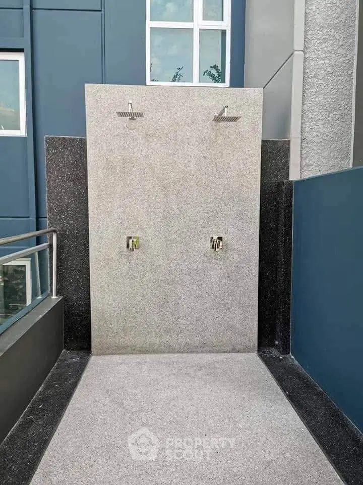 Modern outdoor shower area with sleek design and dual shower heads in a contemporary building.