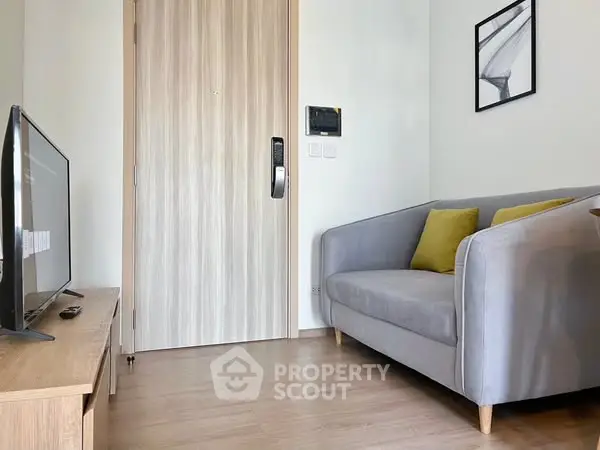 Cozy living room with modern sofa and flat-screen TV, ideal for relaxation.