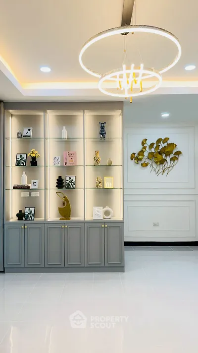Elegant living room with modern chandelier and stylish shelving unit, perfect for contemporary home decor.