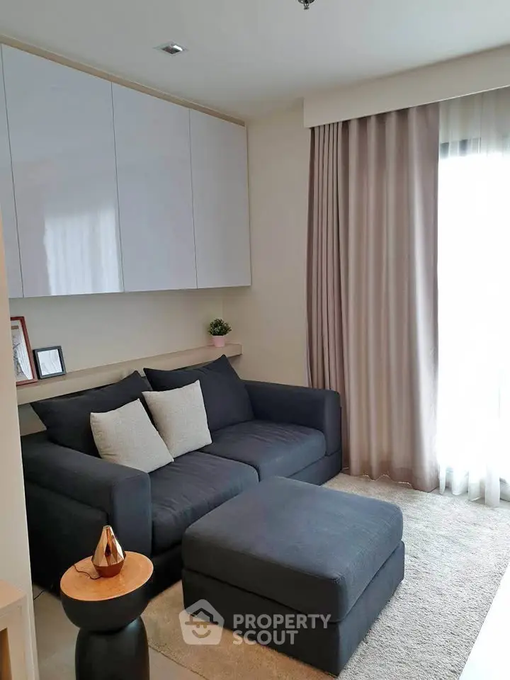 Cozy living room with modern sofa and natural light, perfect for relaxation.