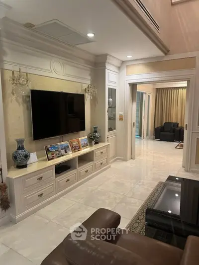 Luxurious living room with elegant decor, large TV, and comfortable seating in a modern apartment.