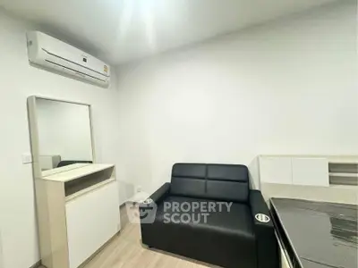 Modern living room with sleek black sofa and air conditioning in a minimalist design.